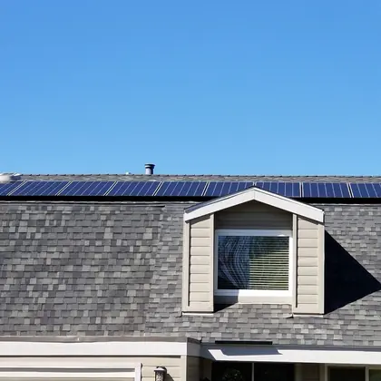 Full row of solar panels along the ridge of a two-story shingle roof