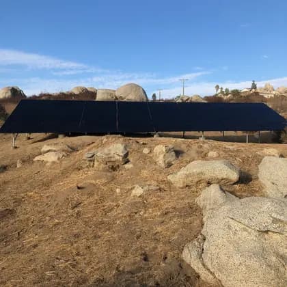 Ground-mounted solar array installed on a rocky boulder-strewn property